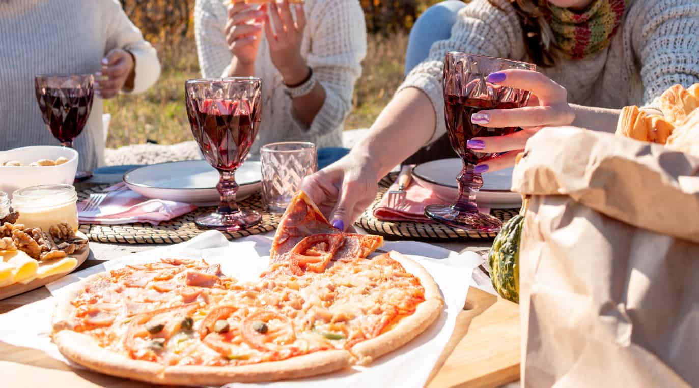 Group of friends having pizza while drinking wine.
